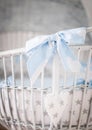 Closeup vertical shot of a white wooden baby basket with a blue bow