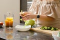 Closeup view of arms of pregnant woman tears iceberg lettuce into pieces in the kitchen