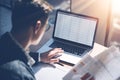 Closeup view of banking finance analyst in eyeglasses working at sunny office on laptop while sitting at wooden table Royalty Free Stock Photo