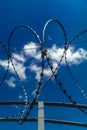 Closeup view of barbed wire fence forming a shape of heart on blue cloudy sky background. Soul barbed wire. Symbol danger warning