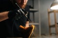 Closeup view of bearded shoemaker wearing black gloves spraying paint of light brown leather shoes, close-up. Royalty Free Stock Photo