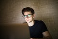 Closeup view of bearded young businessman in eyeglasses working at office at night man using laptop. Hacker Royalty Free Stock Photo