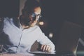 Closeup view of bearded young businessman in eyeglasses working at office at night.Man using laptop.Horizontal, bokeh Royalty Free Stock Photo