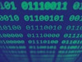 Closeup view of binary computer code with 1s and 0s displayed on a screen with focus blur effect in green and blue