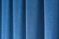 Closeup view of blue curtain in thin and thick vertical folds made of dense fabric.Textured materials and textiles.