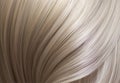 A closeup view of a bunch of shiny straight blond hair in a wavy curved style.