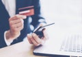 Closeup view of businessman holding credit card in hand and using smartphone,laptop computer on the wooden table.Blurred Royalty Free Stock Photo