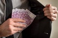 Businessman placing six five hundred Euro bills in the inner pocket of his suit jacket. Conceptual of bribery Royalty Free Stock Photo