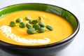 Closeup view of butternut squash cream soup garnished with heavy cream and fresh sunflower microgreen