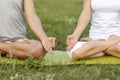 Closeup of couple doing yoga or meditating on grass outdoor. Man and woman in lotus pose making mudras with hands Royalty Free Stock Photo