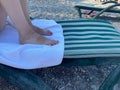 Closeup view of cute small bare feet o little caucasian child sleeping at sunny beach calmly. Legs covered with soft towel Royalty Free Stock Photo