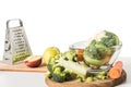 closeup view of cutting boards, grater, bowl, apples, carrot, broccoli and cauliflower on table