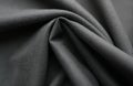 Closeup view of dark grey jersey fabric with soft texture, subtle ribbed pattern. Material drapes, folds, creating shadows, Royalty Free Stock Photo