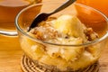 Closeup view of delicious homemade peach cobbler with a scoop of vanilla ice cream and metal spoon in transparent glass bowl on