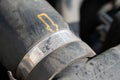 A closeup view of the dusty hose clamp on the car radiator hose, its markings and the yellow dotted arrow