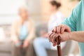 Closeup view of elderly man with cane in nursing home. Assisting senior generation