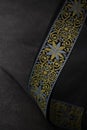 Embroidered guitar strap with decorative yellow and blue pattern on dark fabric surface in soft studio lighting Royalty Free Stock Photo