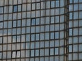 Closeup view of the facade of a commercial high-rise building with sky reflected in the dirty glass elements. Royalty Free Stock Photo