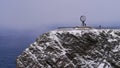 Globe sculpture on cliff on North Cape (Nordkapp), Norway, Scandinavia with two tourists shooting pictures in winter.