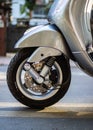 Closeup view of a gray Vespa VXL scooter front tyre and front brake details