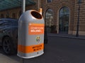Closeup view of a grey and orange colored dustbin in the historic center of Vienna, Austria.