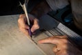 Closeup view of the hands of a Jewish scribe writing the words of the Shema Yisrael prayer on parchment that will be encased in a