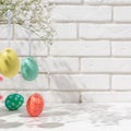 Closeup view of hanging fake eggs on table with brick wall with copy space. Decorated interior