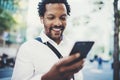 Closeup view of Happy american African man using smartphone outdoor.Portrait of young black cheerful man texting a sms Royalty Free Stock Photo