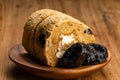 Closeup view of homemade prune sponge cake roll and dried pitted prune fruits in wooden plate
