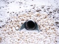 A closeup view of a large storm water drainage culvert pipe emptying into a retention pond set in stone or gravel with snow Royalty Free Stock Photo