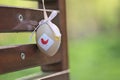 Closeup view of light beige plastic decorative Easter egg tied with ribbon on dark brown bench at university campus Royalty Free Stock Photo