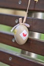 Closeup view of light beige plastic decorative Easter egg tied with ribbon on dark brown bench at university campus Royalty Free Stock Photo