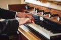 Closeup view on male hands in suit playing at pipe organ in church. Vintage classic musical instrument.