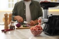 Closeup view of man cutting onion in kitchen, focus on meat grinder Royalty Free Stock Photo
