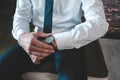 Closeup view of a man dressed in professional attire and fixing his watch seated