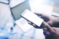 Closeup view of man hands holding modern mobile phone with white clean screen and pointing finger to home button Royalty Free Stock Photo