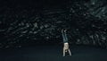 Closeup view of a man handstanding on a rock formation on the black sand beach of Iceland