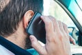 Closeup view of a man holding a mobile phone near his ear and talking on it while driving. Danger of using the phone in a car