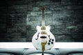 Closeup view of a modern white guitar in a blurred wall background Royalty Free Stock Photo