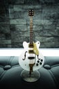 Closeup view of a modern white guitar in a blurred wall background Royalty Free Stock Photo