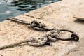 Closeup view of mooring ring and rope tied on it in port of old croatian town Vrsar. Royalty Free Stock Photo