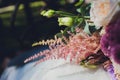 Closeup view of newlyweds hands holding colorful wedding bouquet. Bride and groom wearing wedding rings. Outdoor Royalty Free Stock Photo