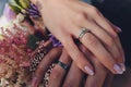 Closeup view of newlyweds hands holding colorful wedding bouquet. Bride and groom wearing wedding rings. Outdoor Royalty Free Stock Photo