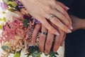 Closeup view of newlyweds hands holding colorful wedding bouquet. Bride and groom wearing wedding rings. Outdoor Royalty Free Stock Photo