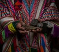 Indigenous farmer in typical traditional handwoven poncho clothes holding potatoes in hands Palccoyo village Cuzco Peru