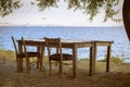 An old rustic wooden table and two chairs by the blue sea and white sky, abandoned. Royalty Free Stock Photo