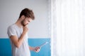 Closeup view of pensive bearded man using tablet while standing near the window in his modern apartment.