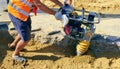 Closeup view of a person operating a vibratory earth rammer compacting the ground on the street, worker body parts are in