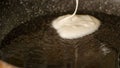 Closeup view pouring fresh white pancake dough mixture into preheat cast iron pan with vegetable oil at home