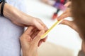 Closeup view of professional manicurist filing fingernail